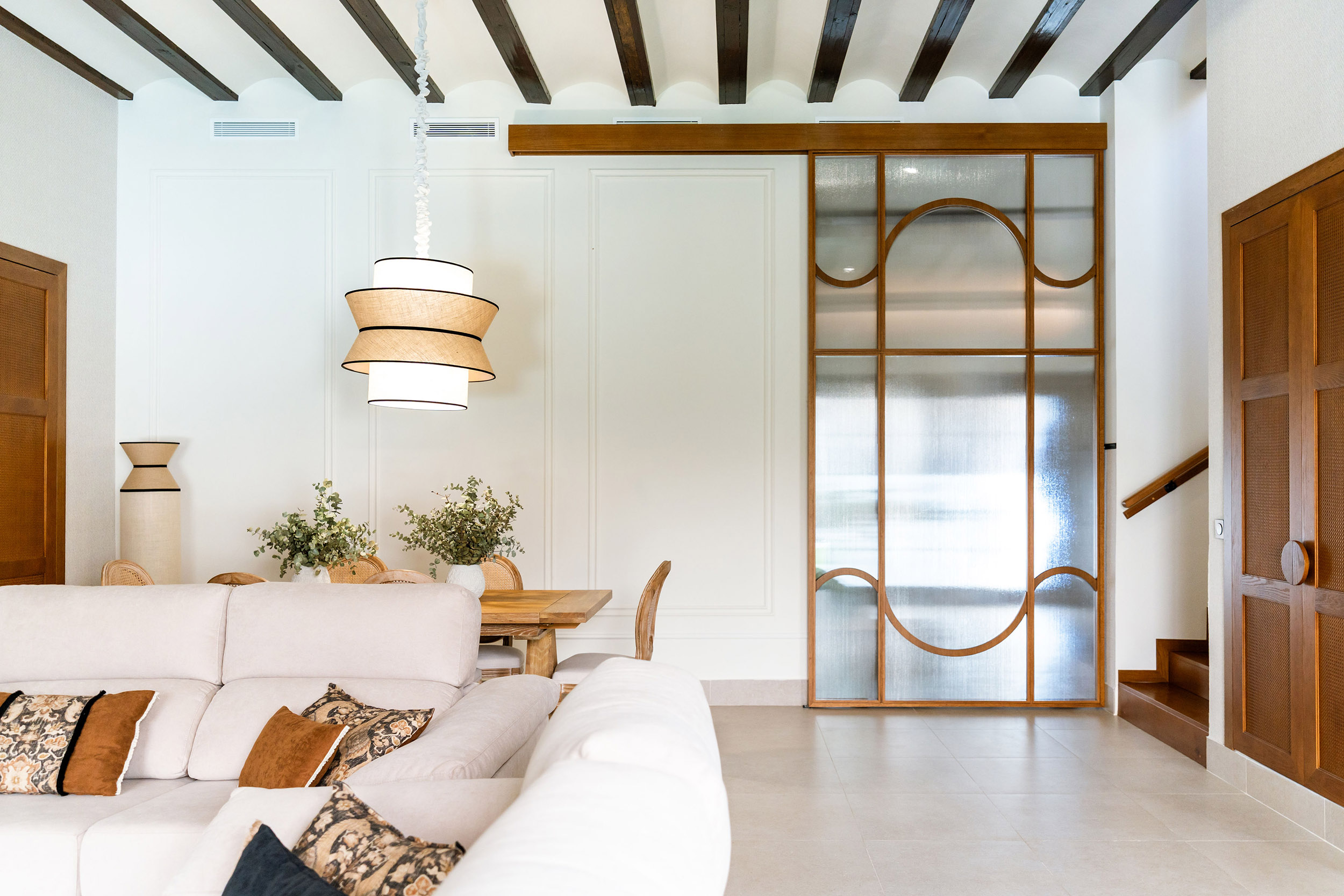 Rehabilitación interior de Casa Sofia: salón comedor abierto a la cocina, con vigas de madera vistas y luz natural.