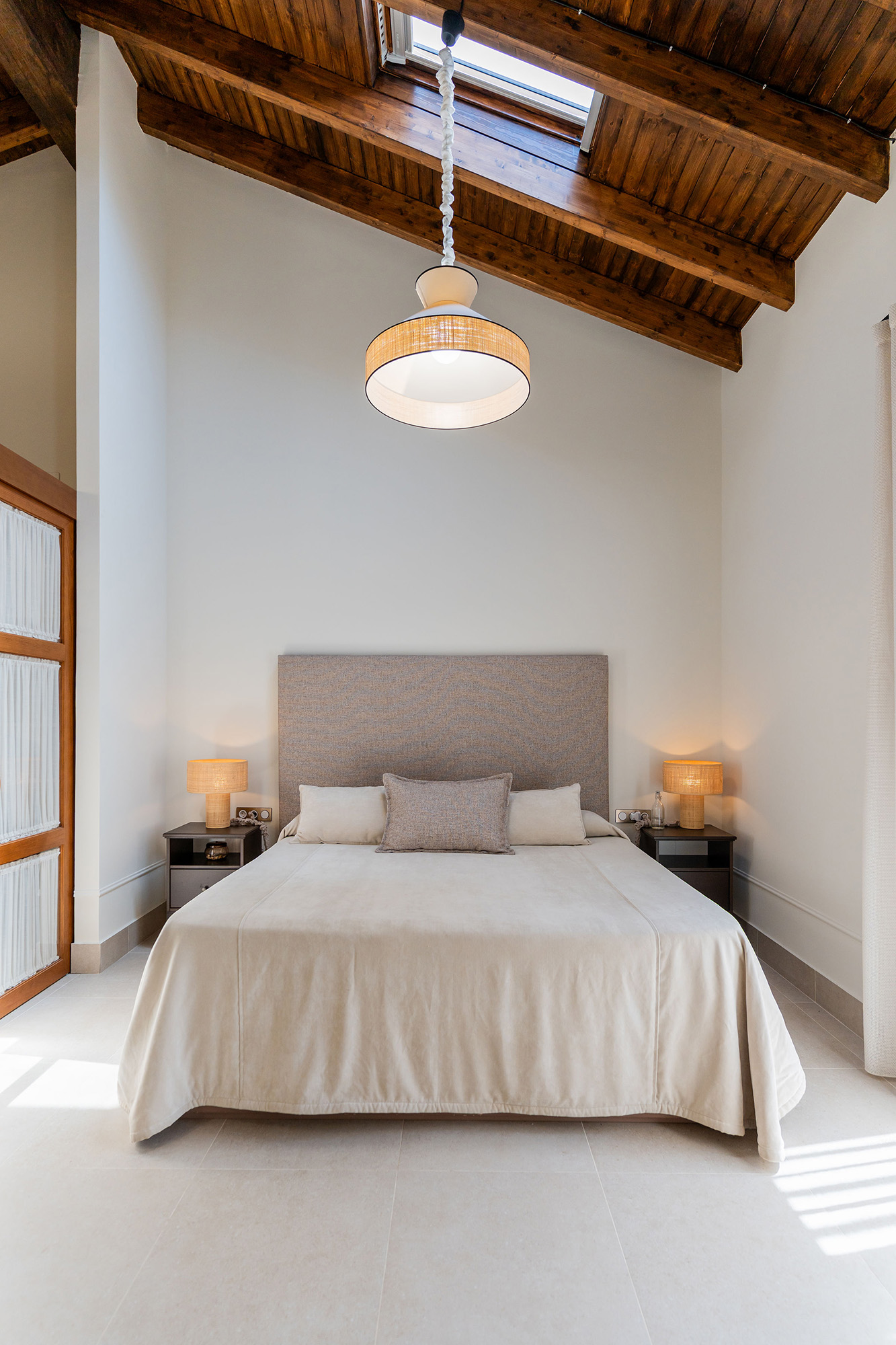 Dormitorio principal de Casa Sofia tras la rehabilitación integral, con cubierta inclinada de madera vista y luz natural.