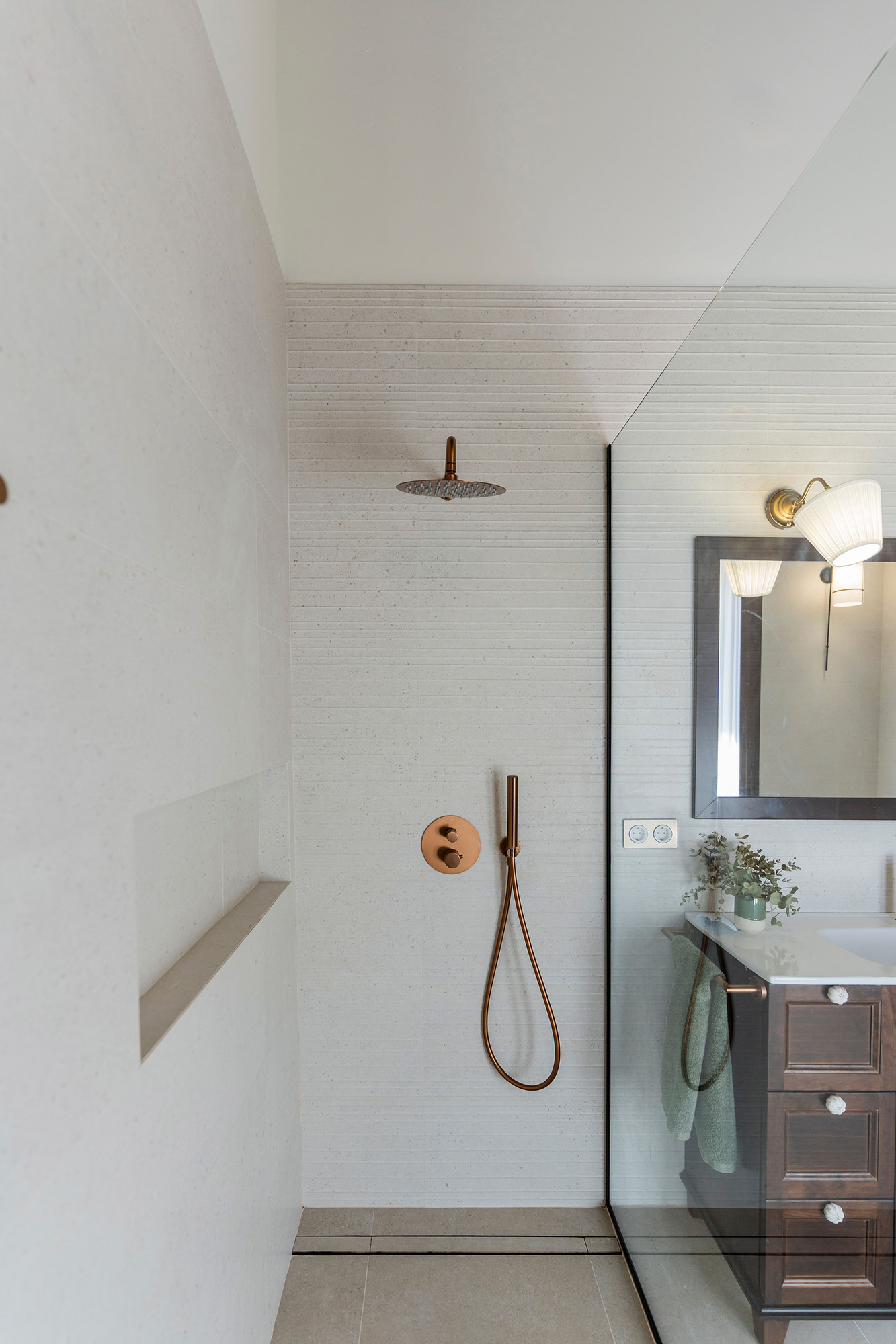 Baño reformado de Casa Sofia con ducha a ras de suelo, revestimientos claros, mueble de madera y techo con vigas vistas.