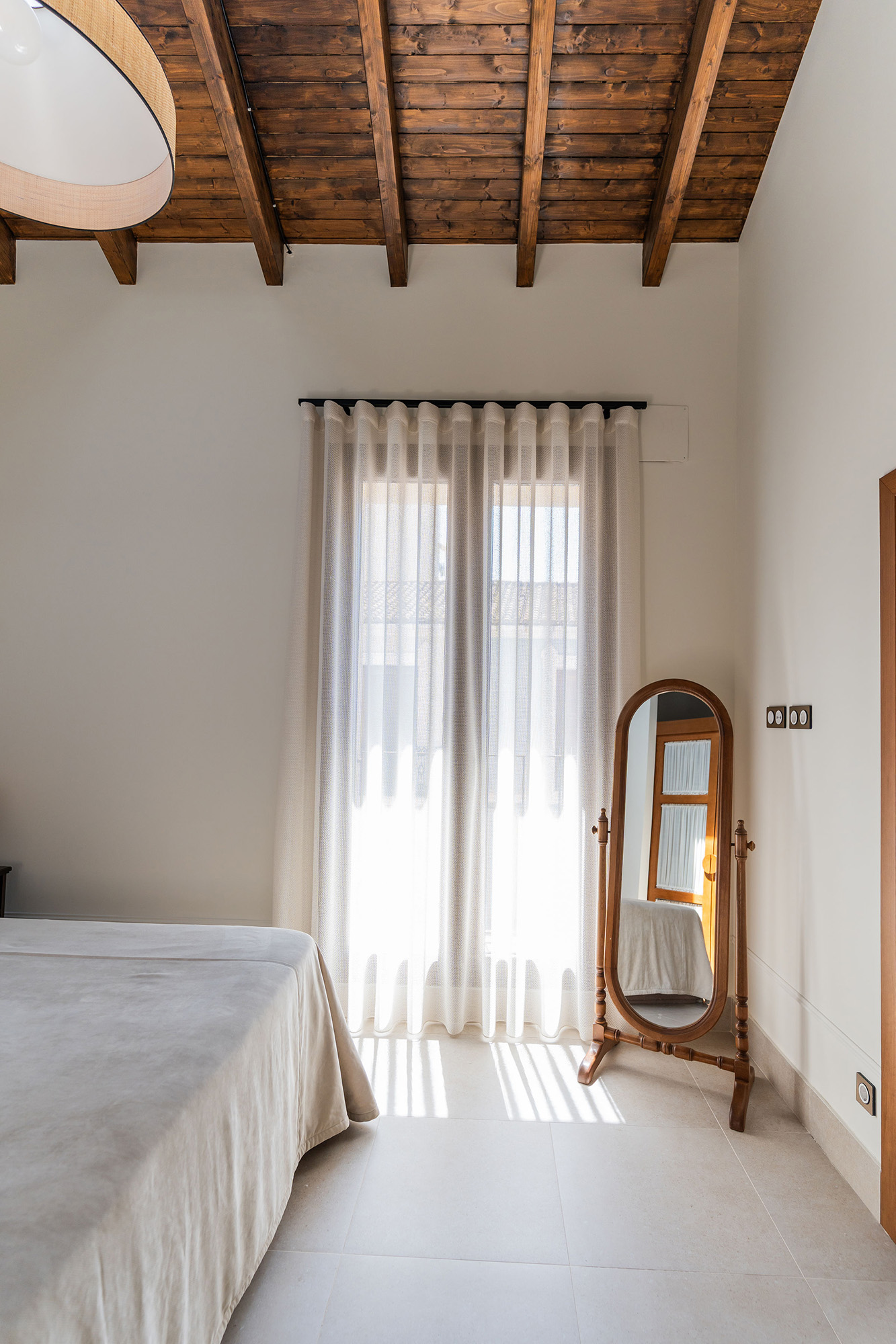 Dormitorio principal de Casa Sofia tras la rehabilitación integral, con cubierta inclinada de madera vista y luz natural.
